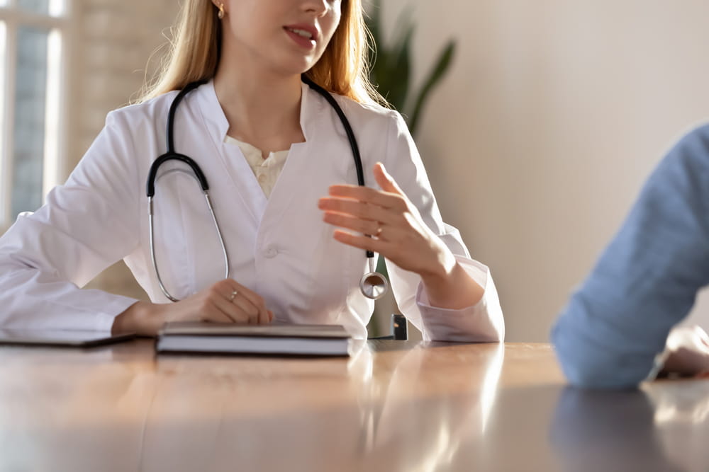 Close up of young female doctor in white medical uniform consult patient in private clinic
