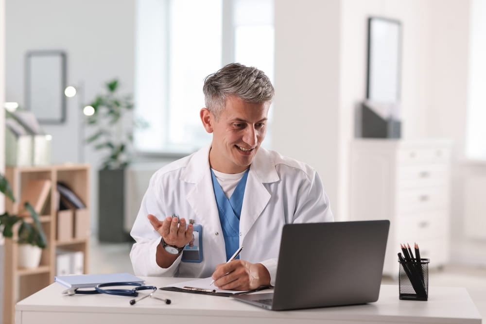 Telemedicine. Doctor having video call with patient via laptop indoors
