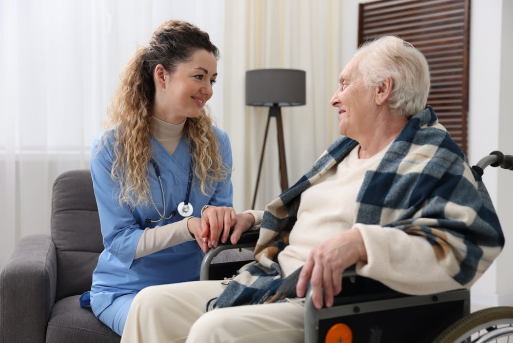 Care worker checking senior woman's pulse in wheelchair indoors