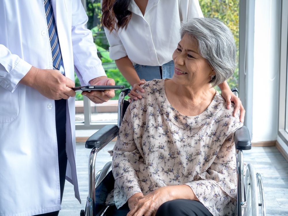 Portrait of smiling senior woman patients in wheelchair with assistant take her to meet doctor