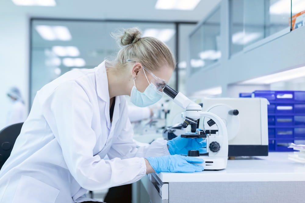 Caucasian scientist looking through a microscope in a laboratory