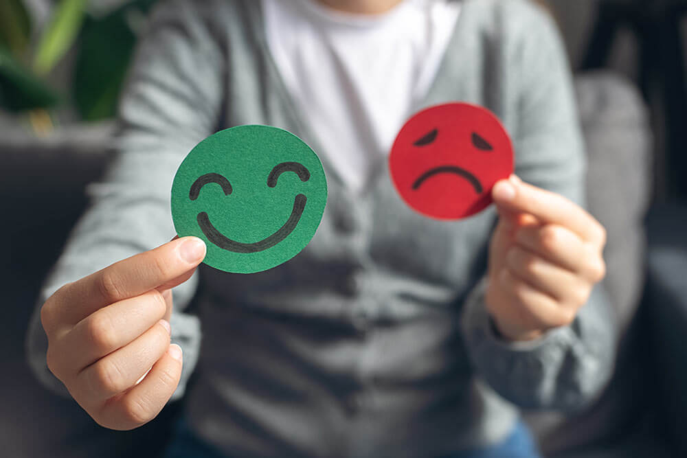 Female hands holding happy and sad face paper