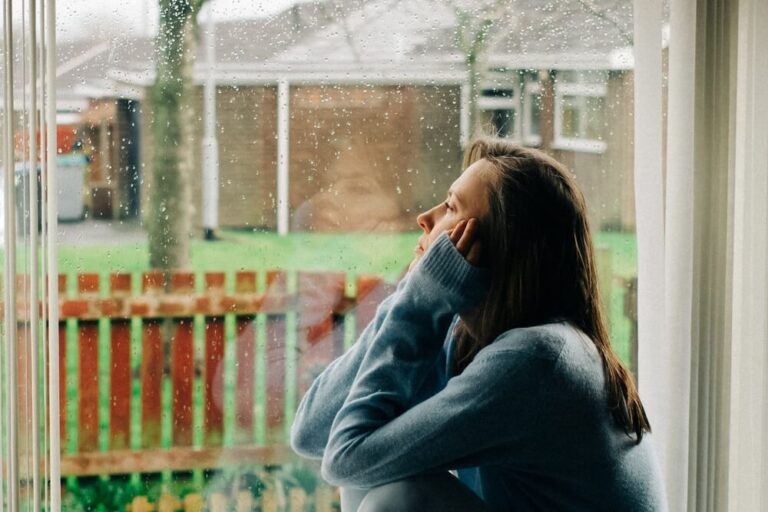 sad woman sitting on a windowsill