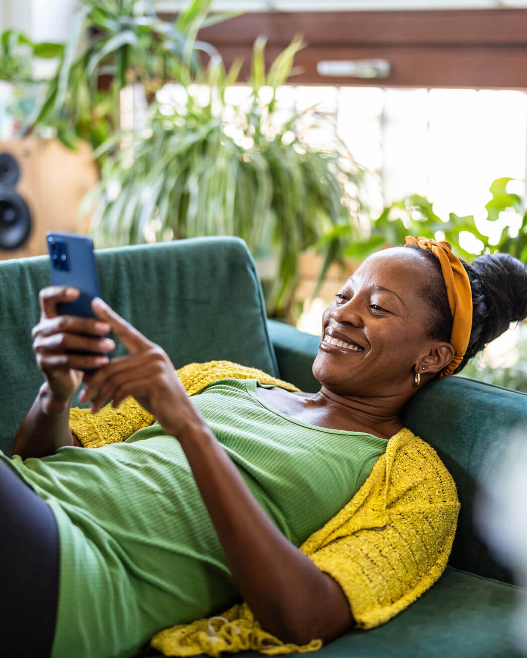 Woman using smartphone while relaxing on sofa at home