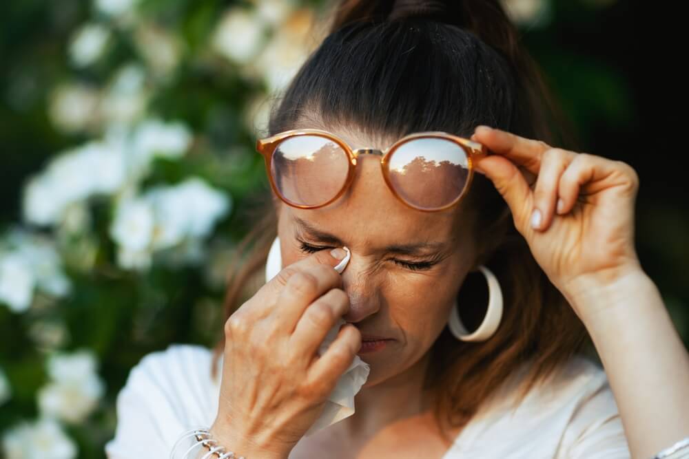 Woman in white shirt with handkerchief and eyeglasses has an allergy attack