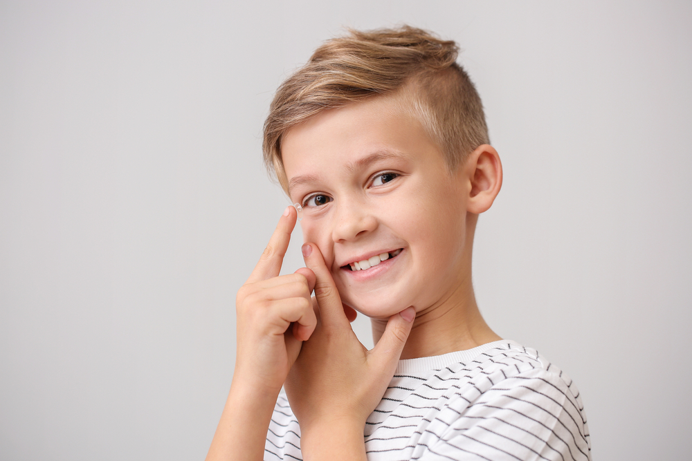 Little boy putting in contact lens