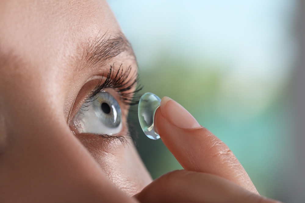 Young woman putting contact lens in her eye