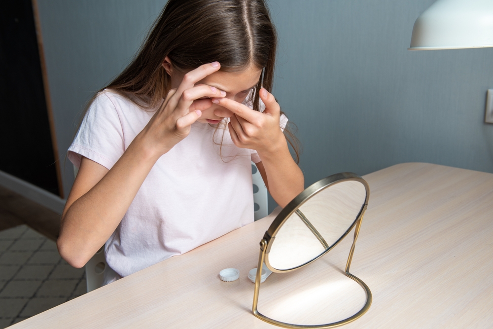 Little child putting contact lens into her eye