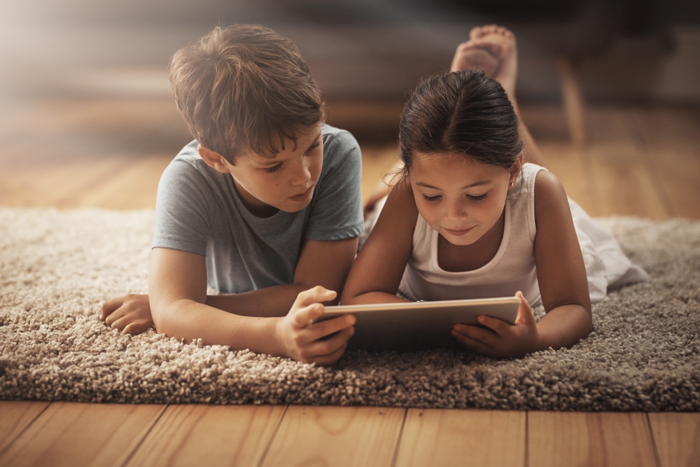 Kids watching video with tablet on floor for digital education