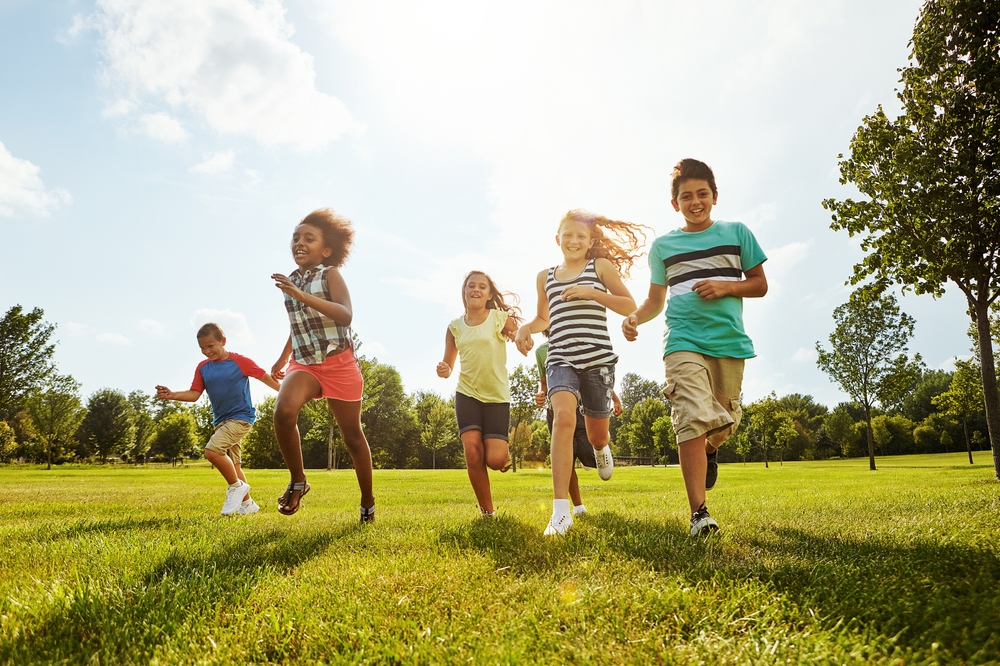 Happy kids running with friends in nature for fun