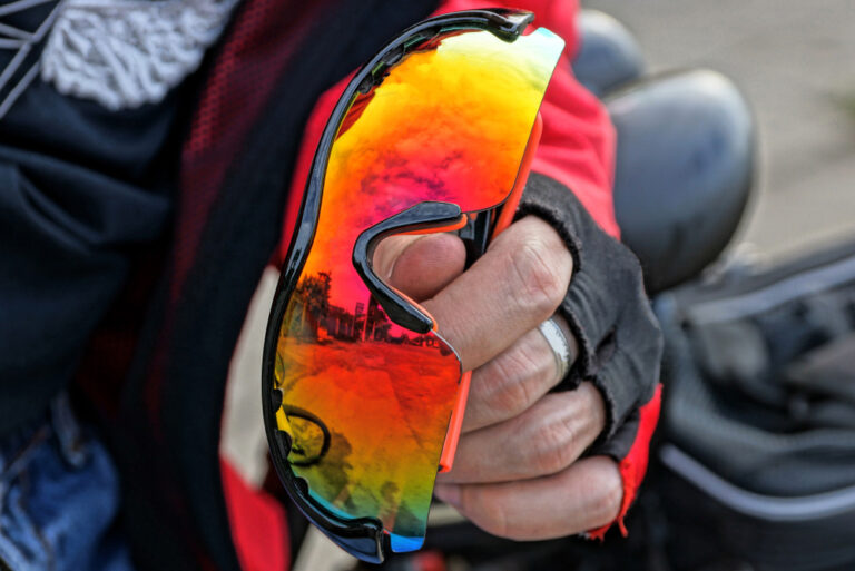 gloved hand holds colored sport glasses outside