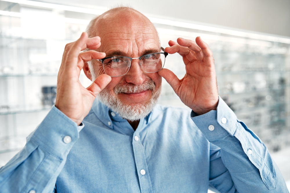 Mature man senior choosing optical glasses for himself in a professional store. Vision correction and ophthalmology.