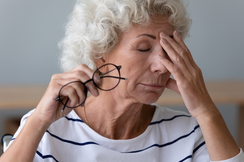 Exhausted mature woman take off glasses suffer from blurry vision or dizziness