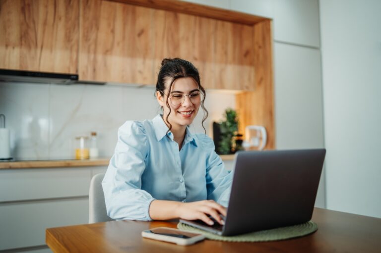 Young caucasian business woman wearing glasses and working on laptop from home during the day