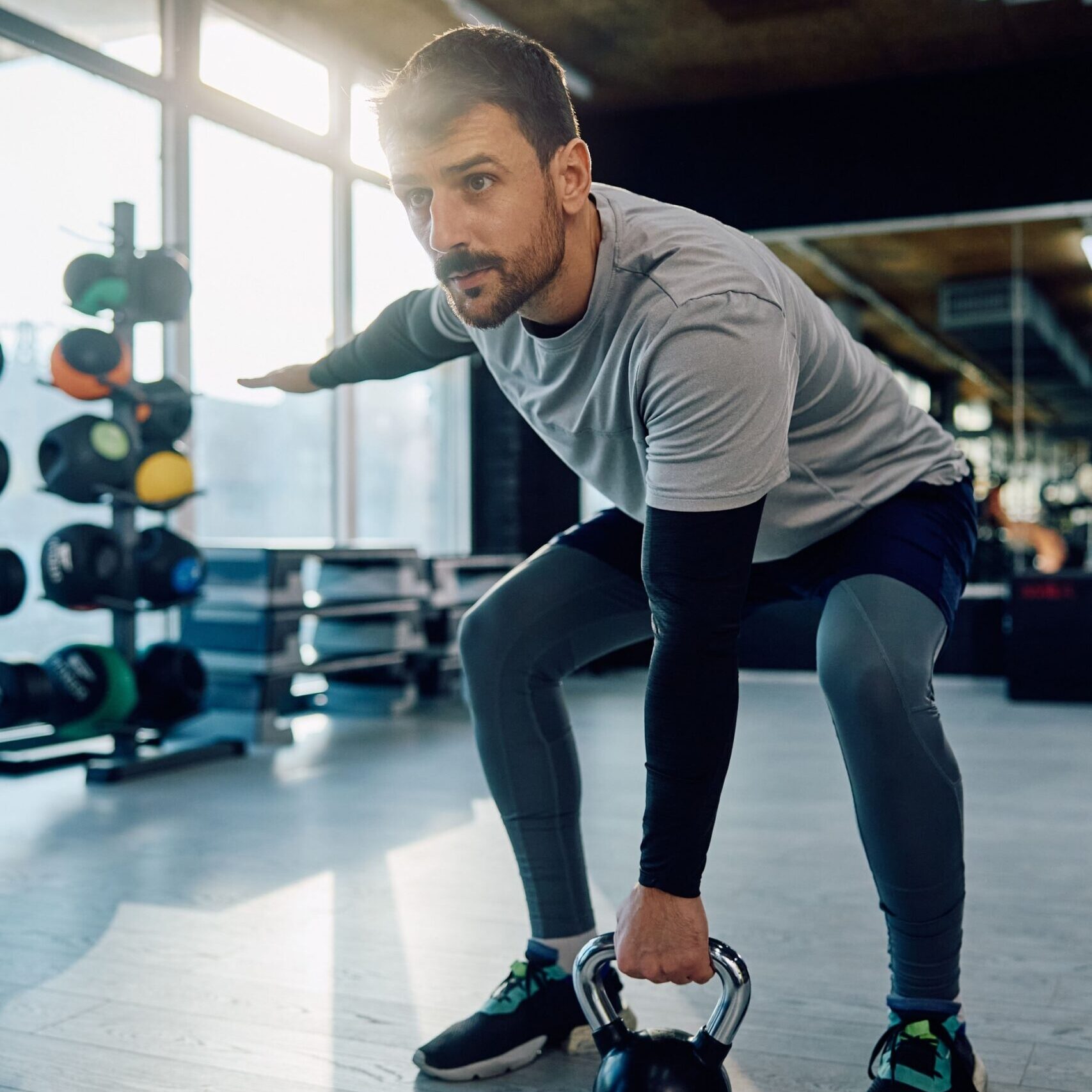 Athletic man exercising with kettlebell while working out in health club