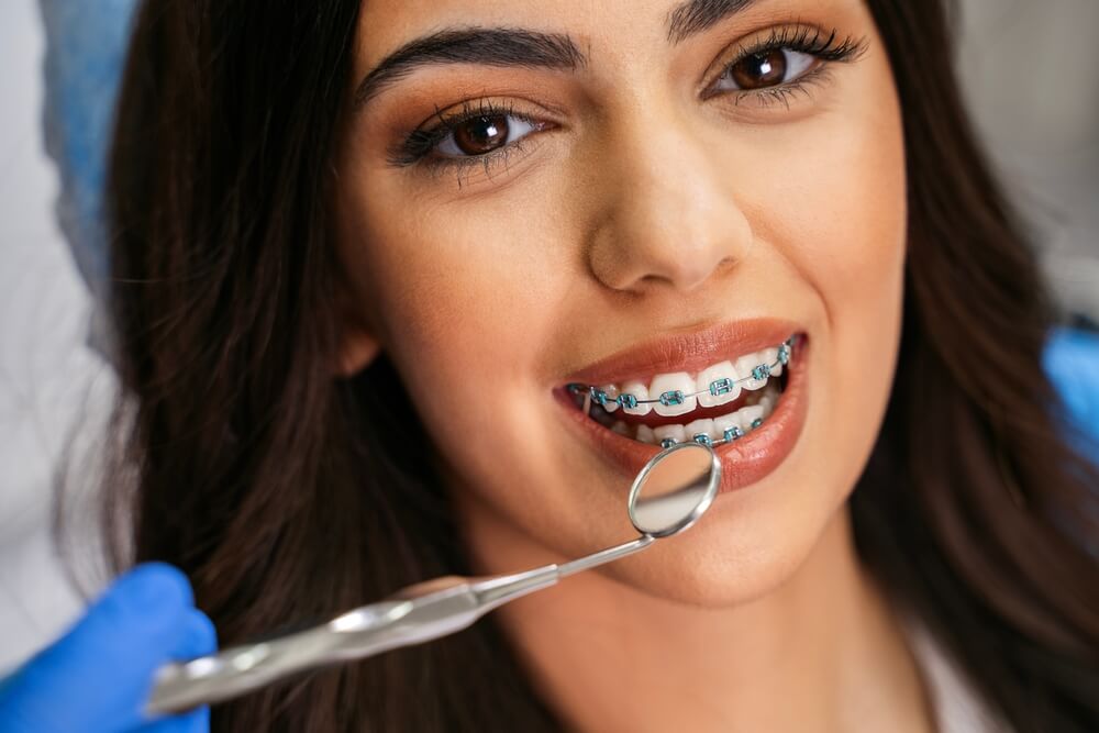 Charming young woman with dental braces having checkup