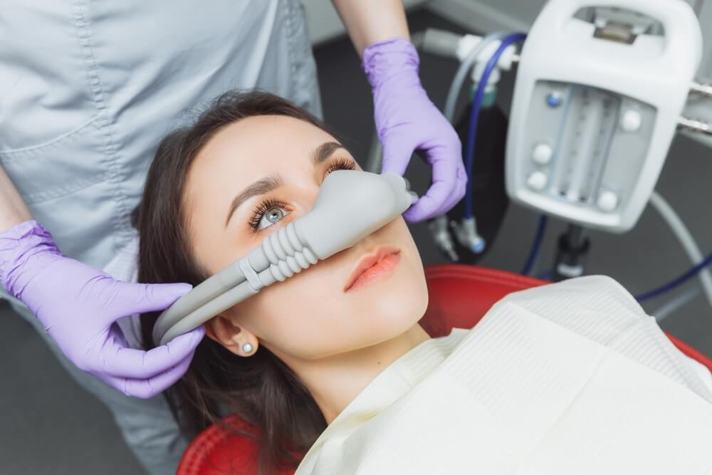 Dentist puts inhalation sedative mask on his patient