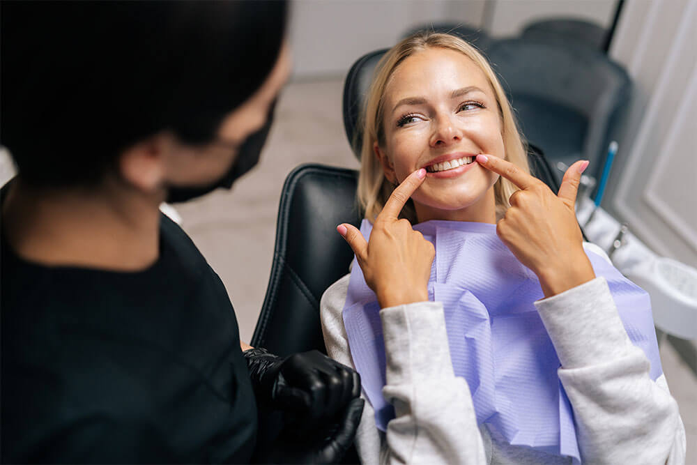 happy young woman patient pointing with fingers at healthy smile