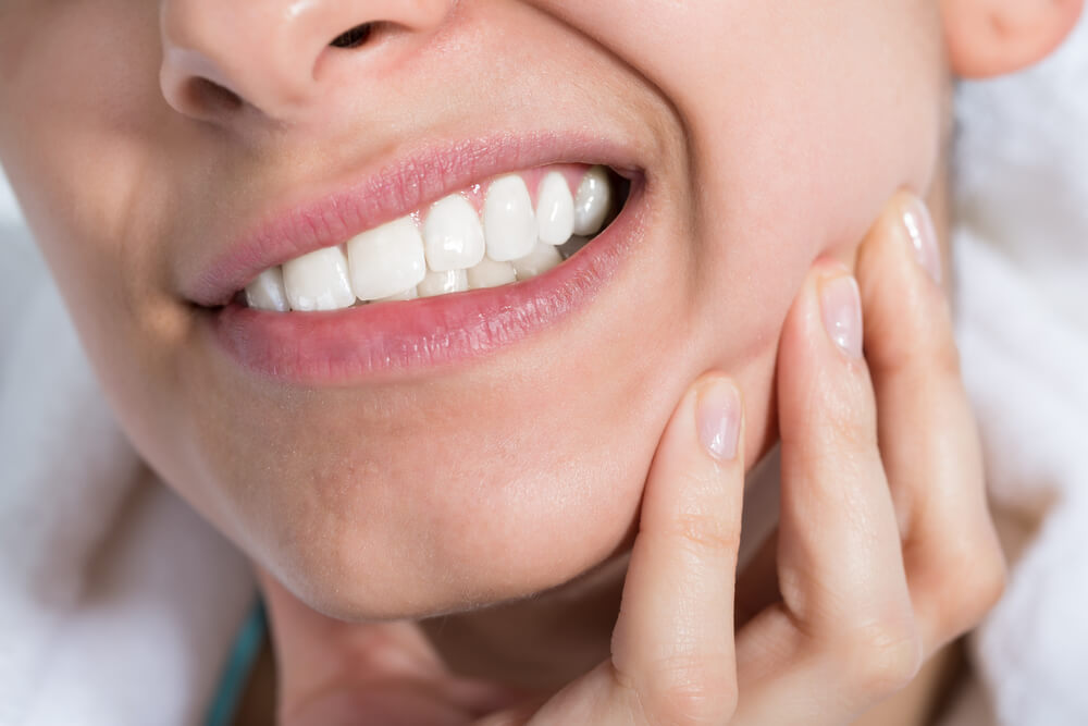 young woman suffering from toothache at home