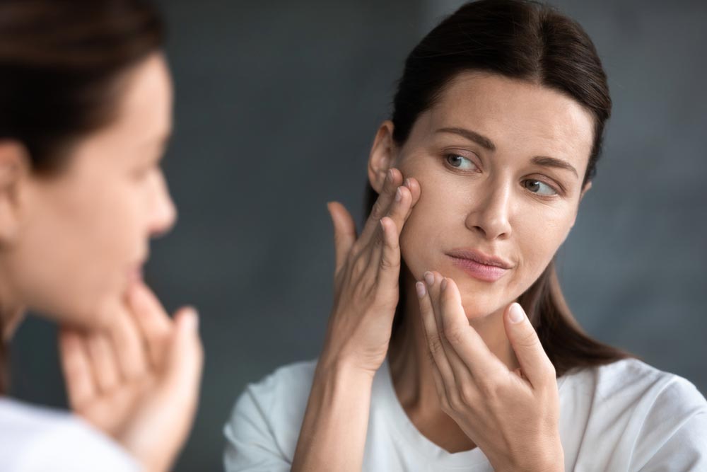 woman looking at her face in mirror