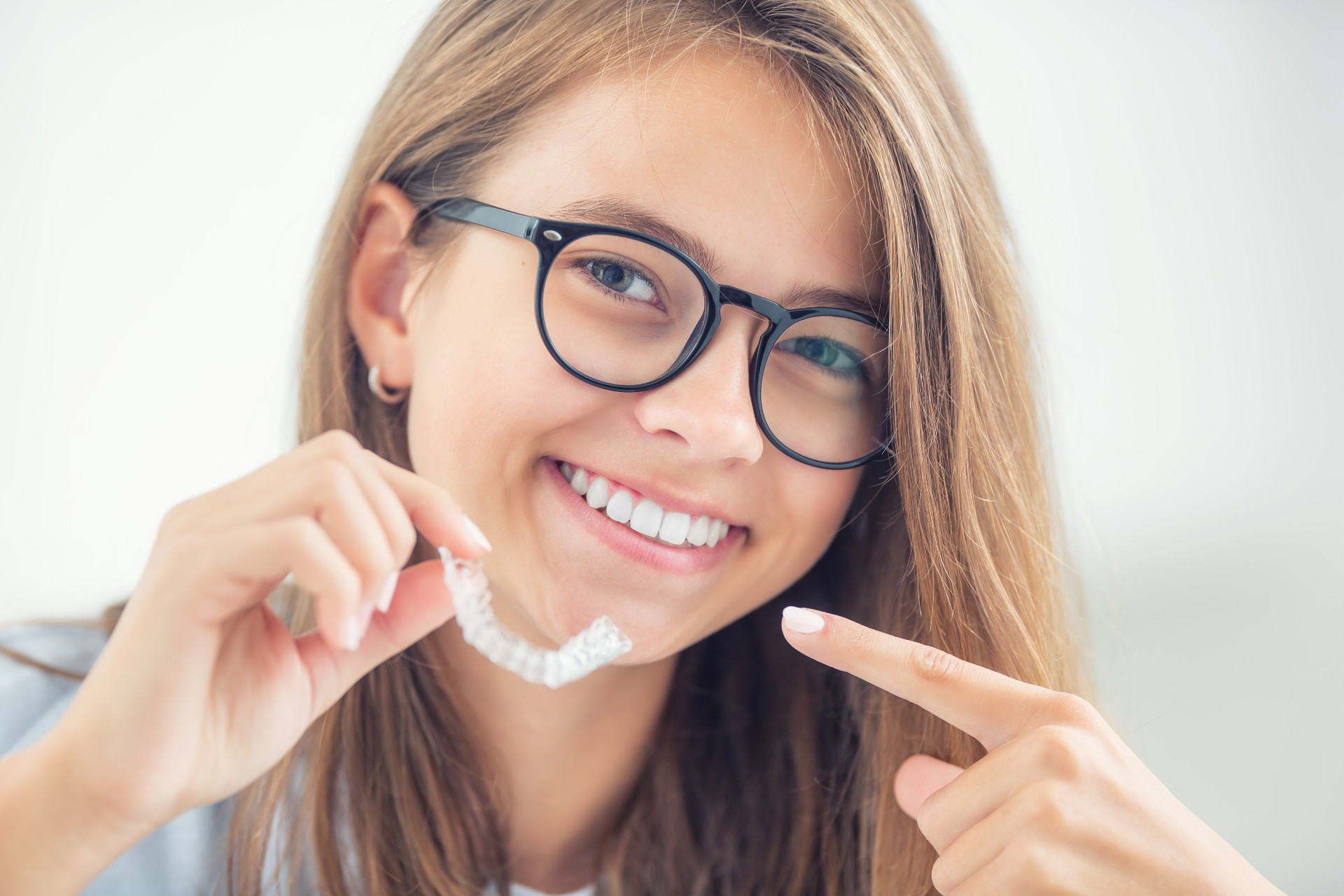 Teen holding invisaligner