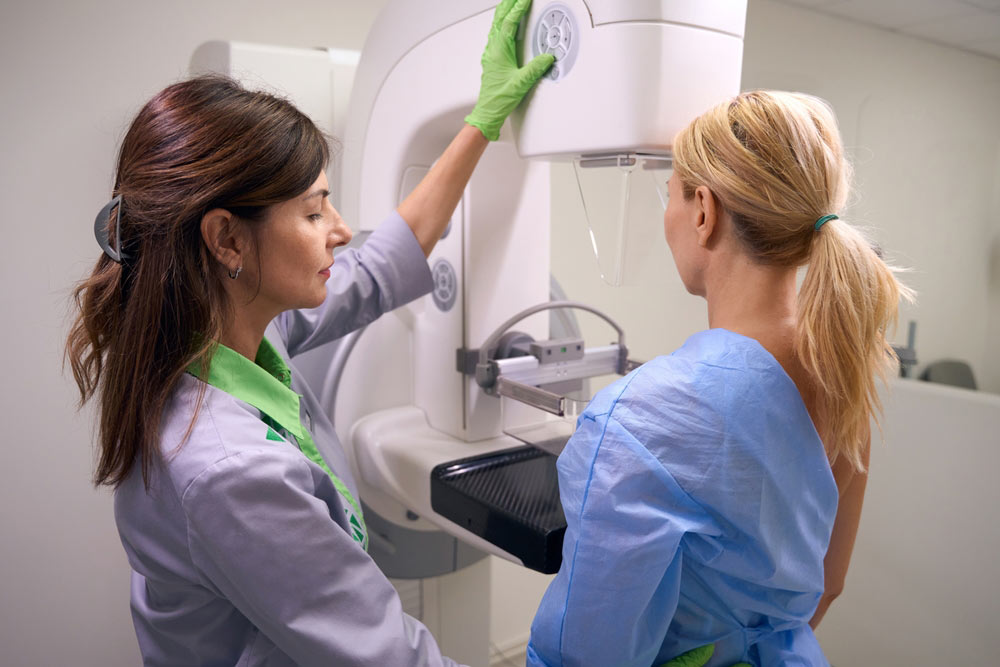 Qualified mammographer preparing woman for screening mammogram
