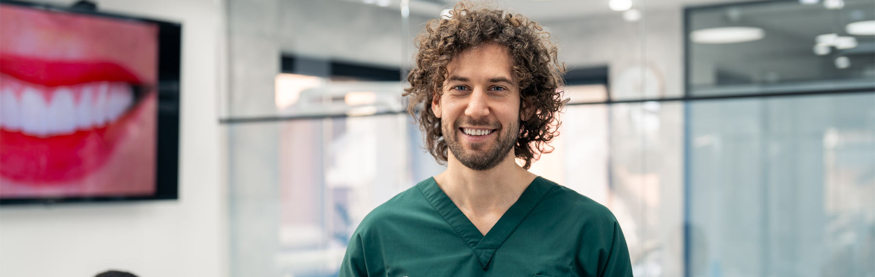 happy male professional dentist with digital tablet standing in his dental office