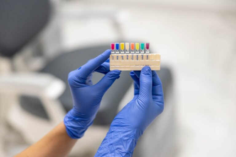Close-up of a dental professional's gloved hands holding dental color matching tools, used for creating precise dental restorations like crowns or veneers.