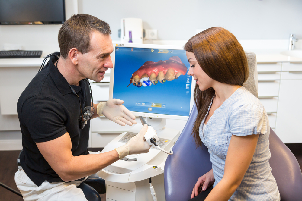 Dentist counseling patient about CEREC (Chairside Economical Restoration of Esthetic Ceramics) dental technology