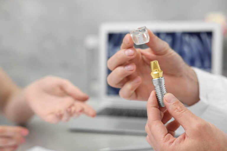 Doctor with educational model of dental implant consulting patient in clinic, closeup. Space for text
