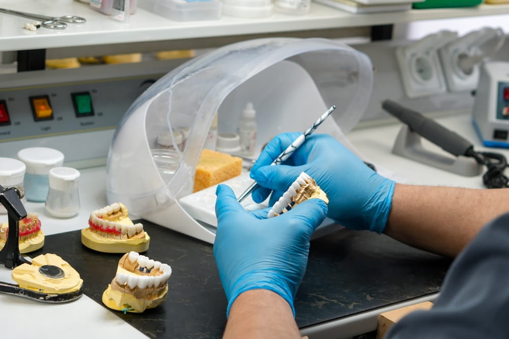 Dental prosthesis work. Denture work. Teeth painting. Dental technician working with tooth denture at prosthesis laboratory