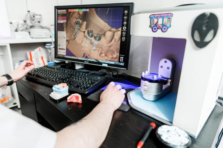 Dental technician using software to design teeth and prosthetics with models and scanne