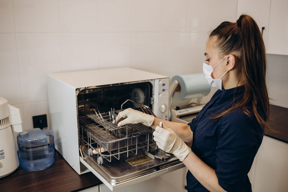 The dental assistant takes the disinfected instrument out of the sterilizer. Sterile dental instrument