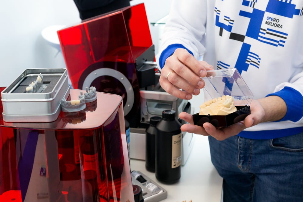 High-accuracy 3D printing materials for dental labs. A man shows the operation of a 3D printer in dentistry