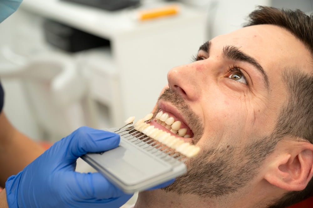 Dentist matching patient's teeth color with shade guide in clinic