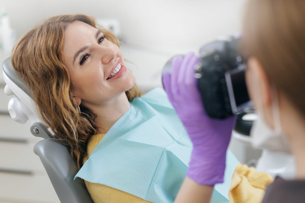 Dentist photographing of teeth woman client after treatment at dental clinic.