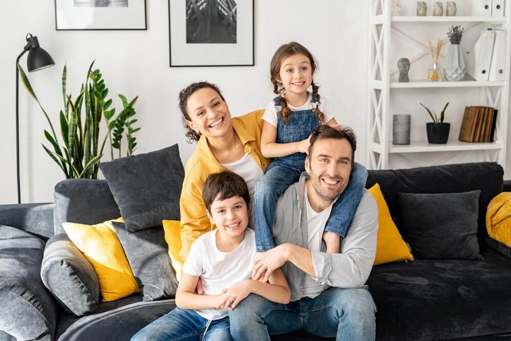 Happy family of four sitting on the sofa in cozy living room