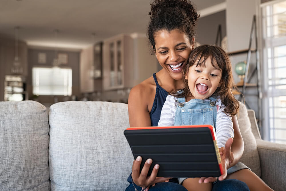 mother and smiling daughter playing on digital tablet