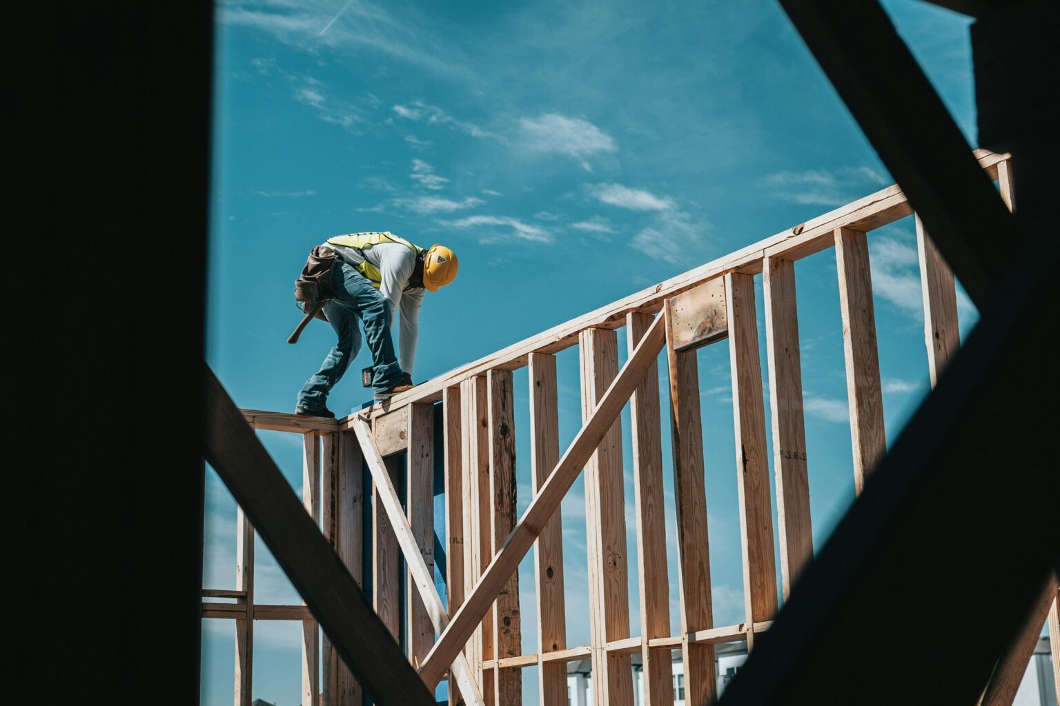 A construction worker wearing a safety vest is working on a building site