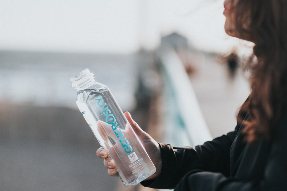 Woman holding water bottle standing at bridge