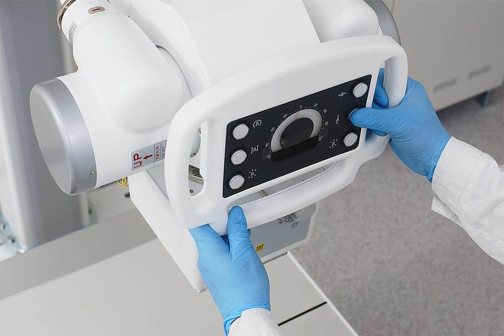 medical worker's hands in an x-ray room preparing x-ray equipment for scanning