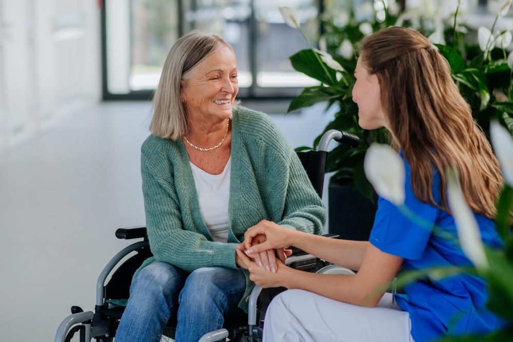 Young woman doctor taking care of senior woman at wheelchair