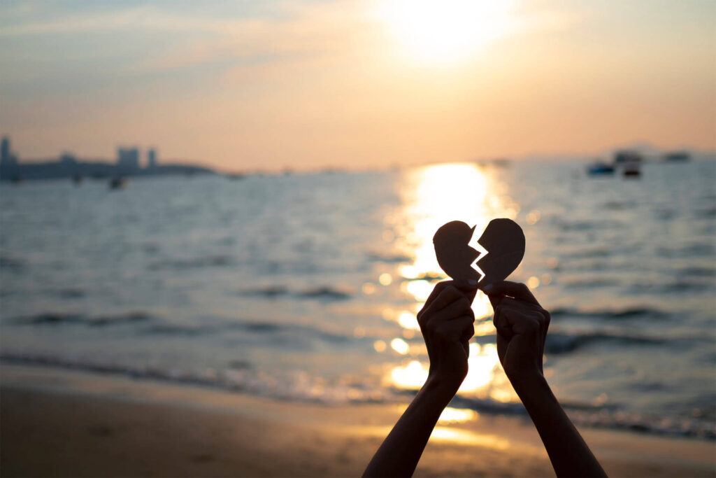 two hands holding broken heart shape with sunset