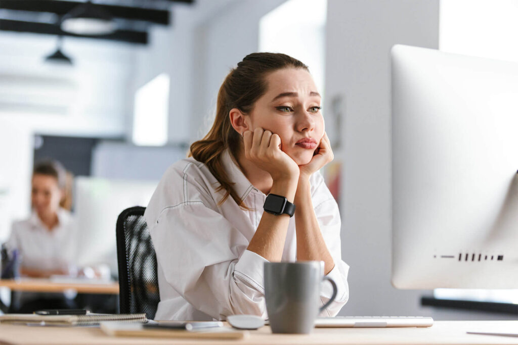 Bored young woman sitting at her workplace at the office