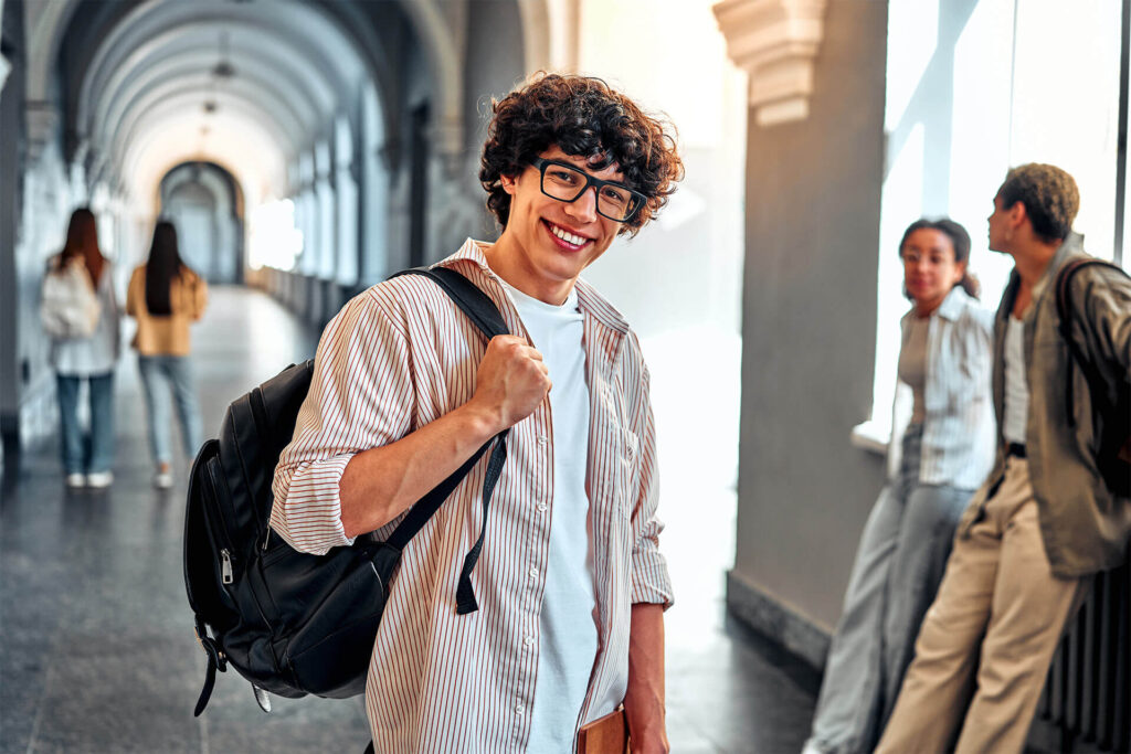 smiling curly-haired student in glasses with a backpack