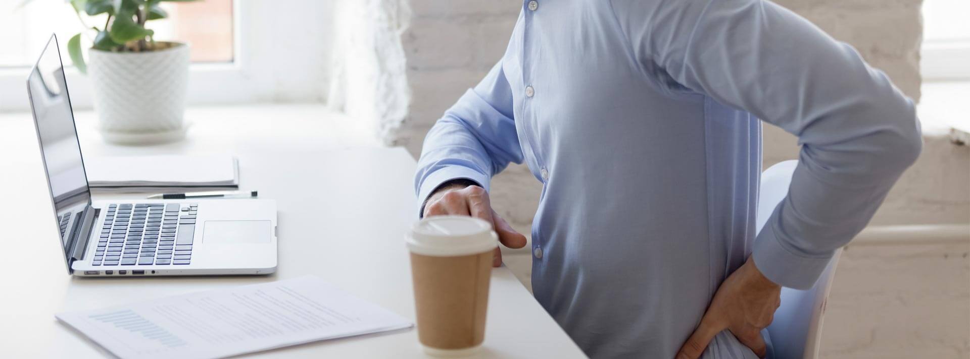Unhealthy office worker sitting at desk opposite computer feels sudden sharp pain