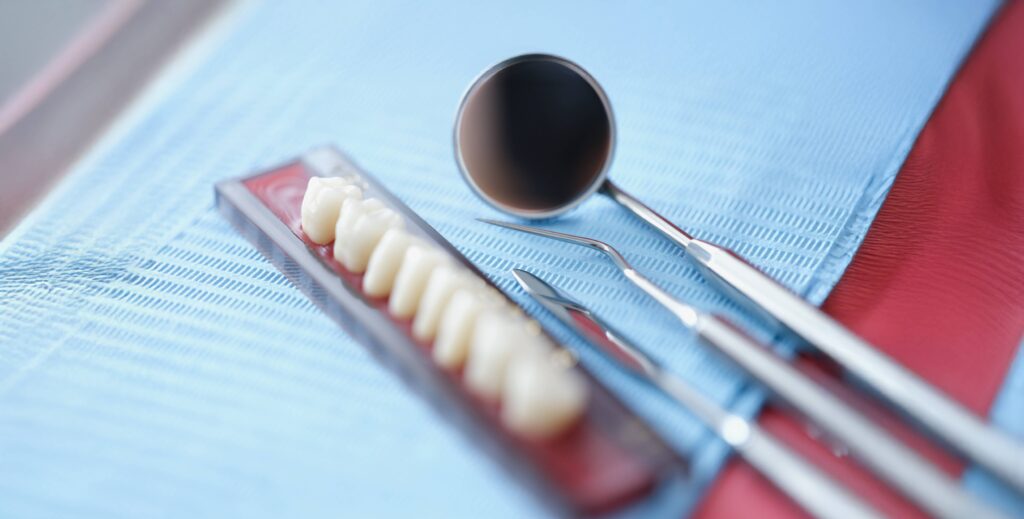 Orthodontist tools and dental bridge, close-up, blurry