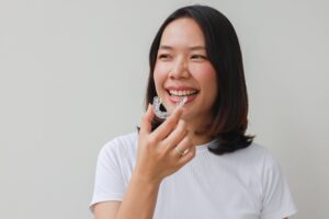 close up young lovely asian woman hand holding dental aligner retainer