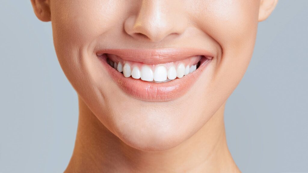 Woman mouth smiling. Her teeth are white and healthy, and she has a gentle smile on her face.