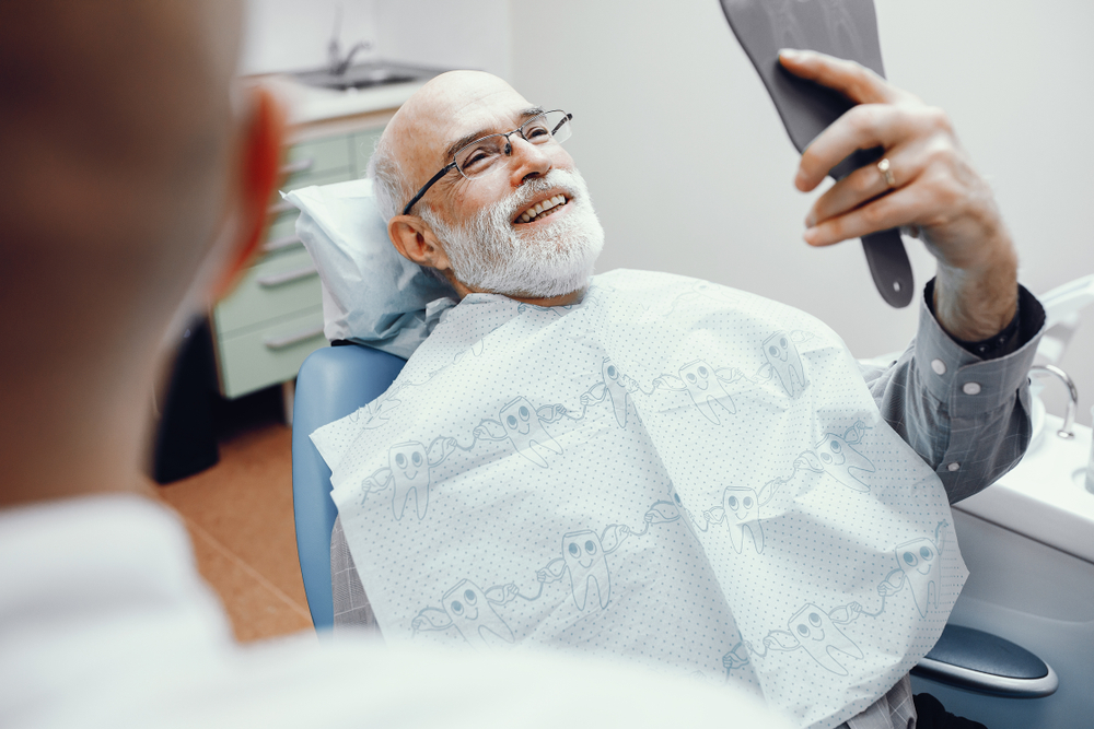 Two men in the dentist's office. Grandfather looking into the mirror on his teeth